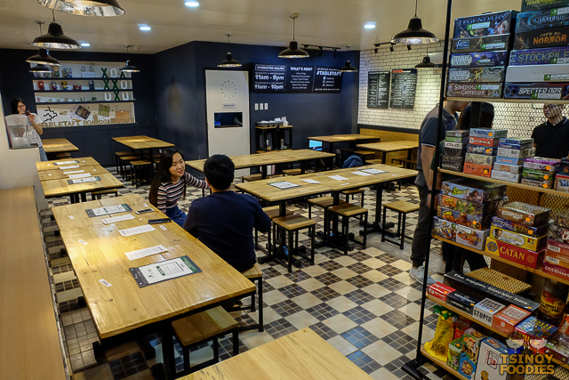Interior of a board game café with game shelves and shared tables, illustrating the local venue model discussed in this comparison