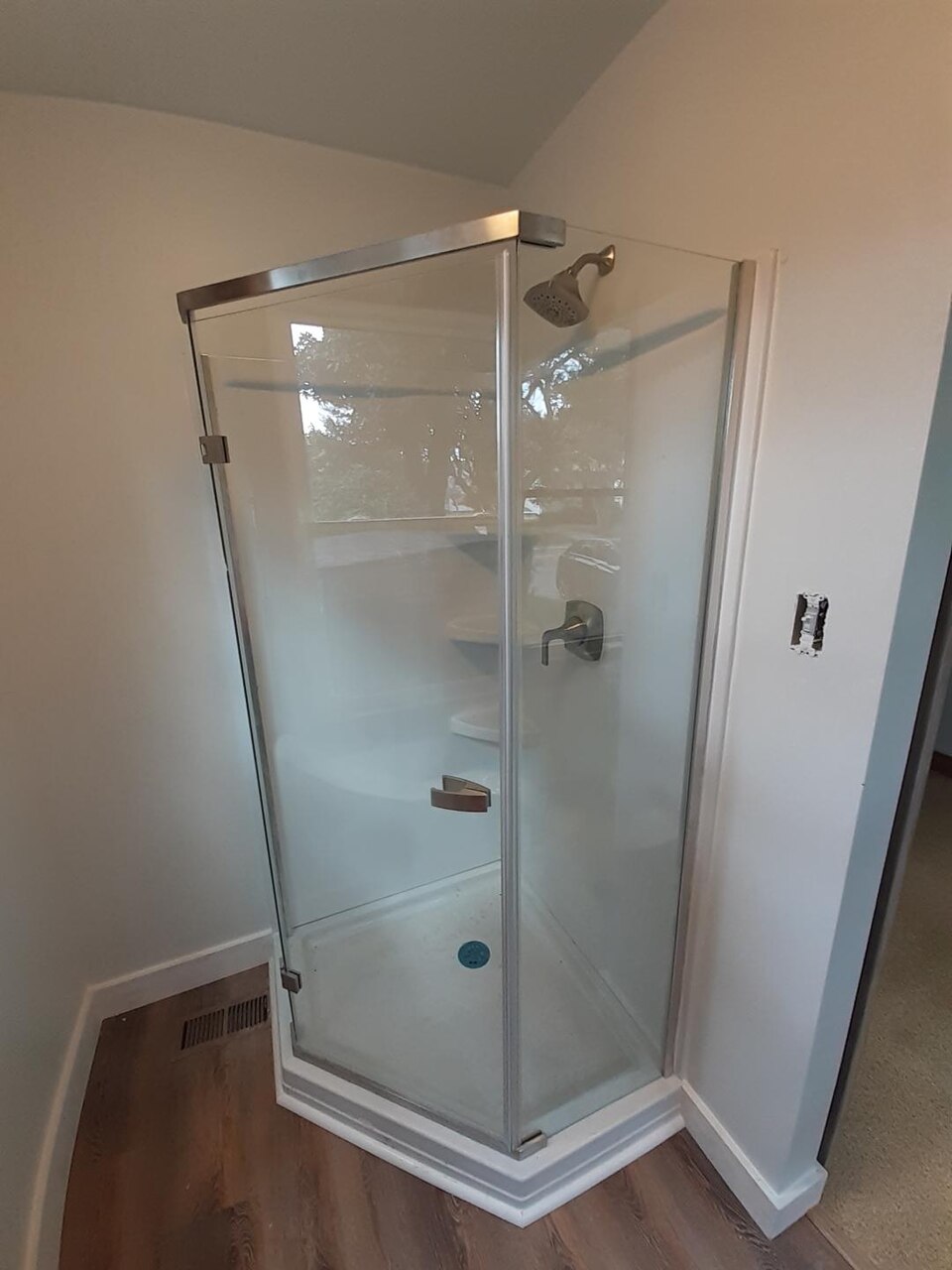 Corner shower enclosure with a hinged door, metal frame and a frosted band across the glass