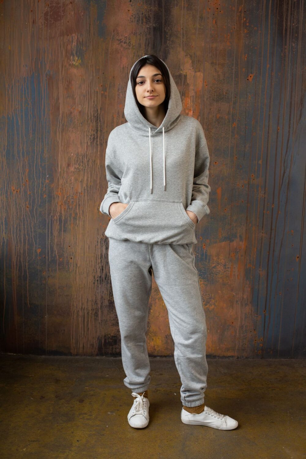 Woman wearing a grey hoodie and relaxed cuffed sweatpants with white sneakers