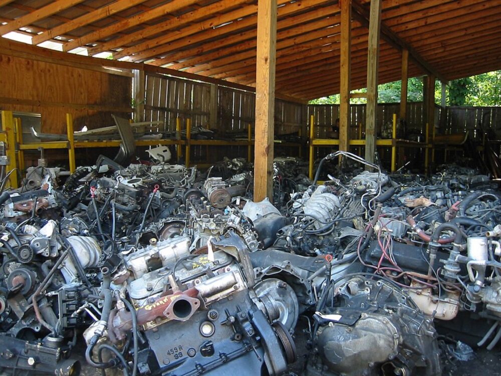 Used car engines stacked in a wrecking yard, illustrating self-serve auto recyclers like Harvey Wreckers
