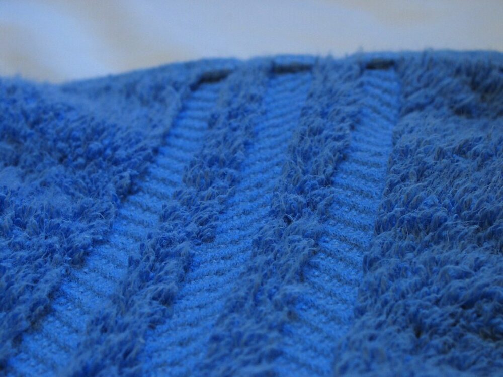 Close-up of blue towel texture with decorative pattern, illustrating loop construction and weave quality.