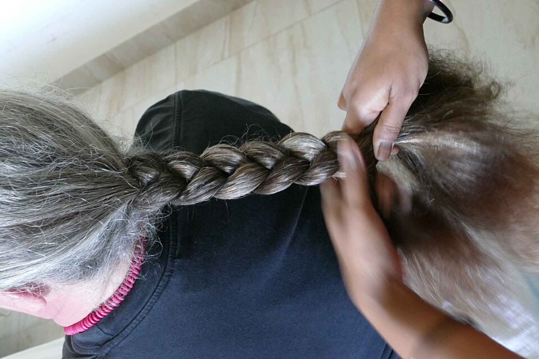 braiding hair being styled, illustrating cost per service decisions