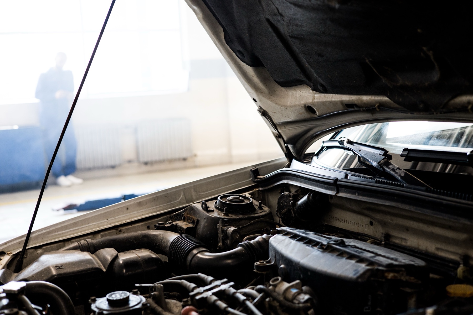 Mechanic holding an auto part in a workshop, representing online sourcing concerns for St and auto parts