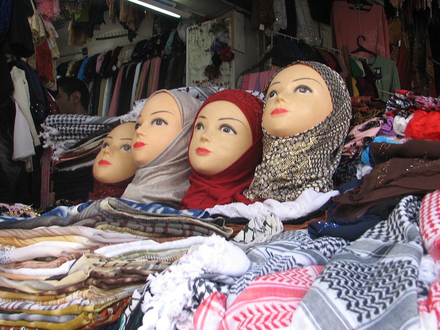 Assorted hijabs in different colors and fabrics displayed on shelves