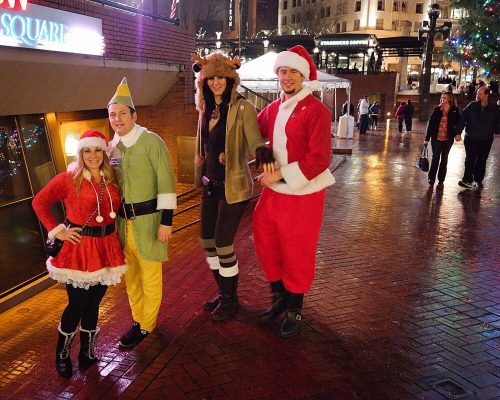 Four adults wearing festive Christmas costumes outdoors