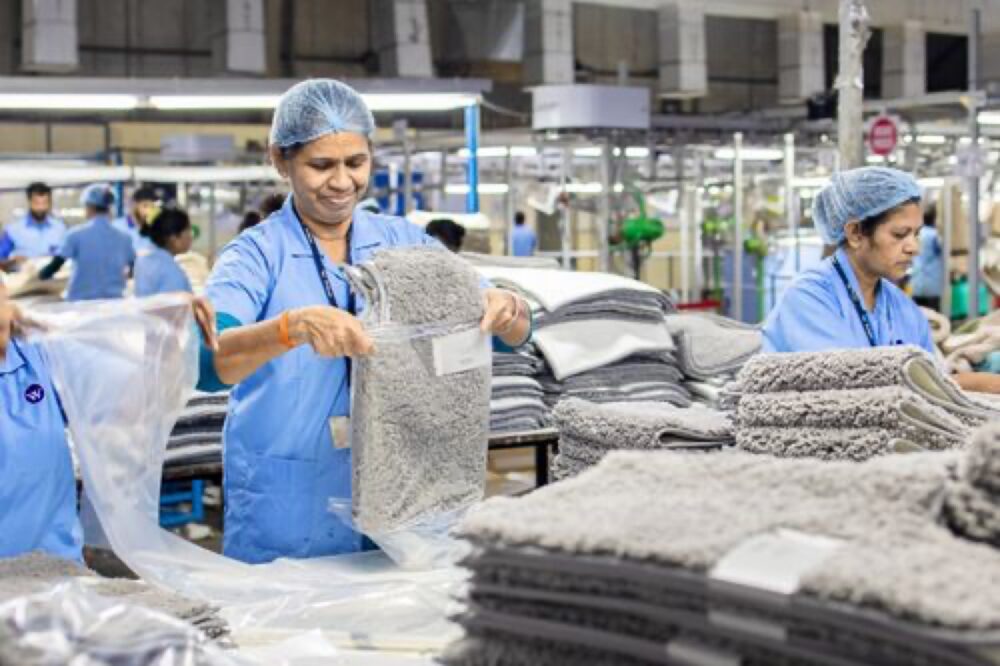 Workers in a textile factory organizing rugs, illustrating the upstream side of area rug sourcing