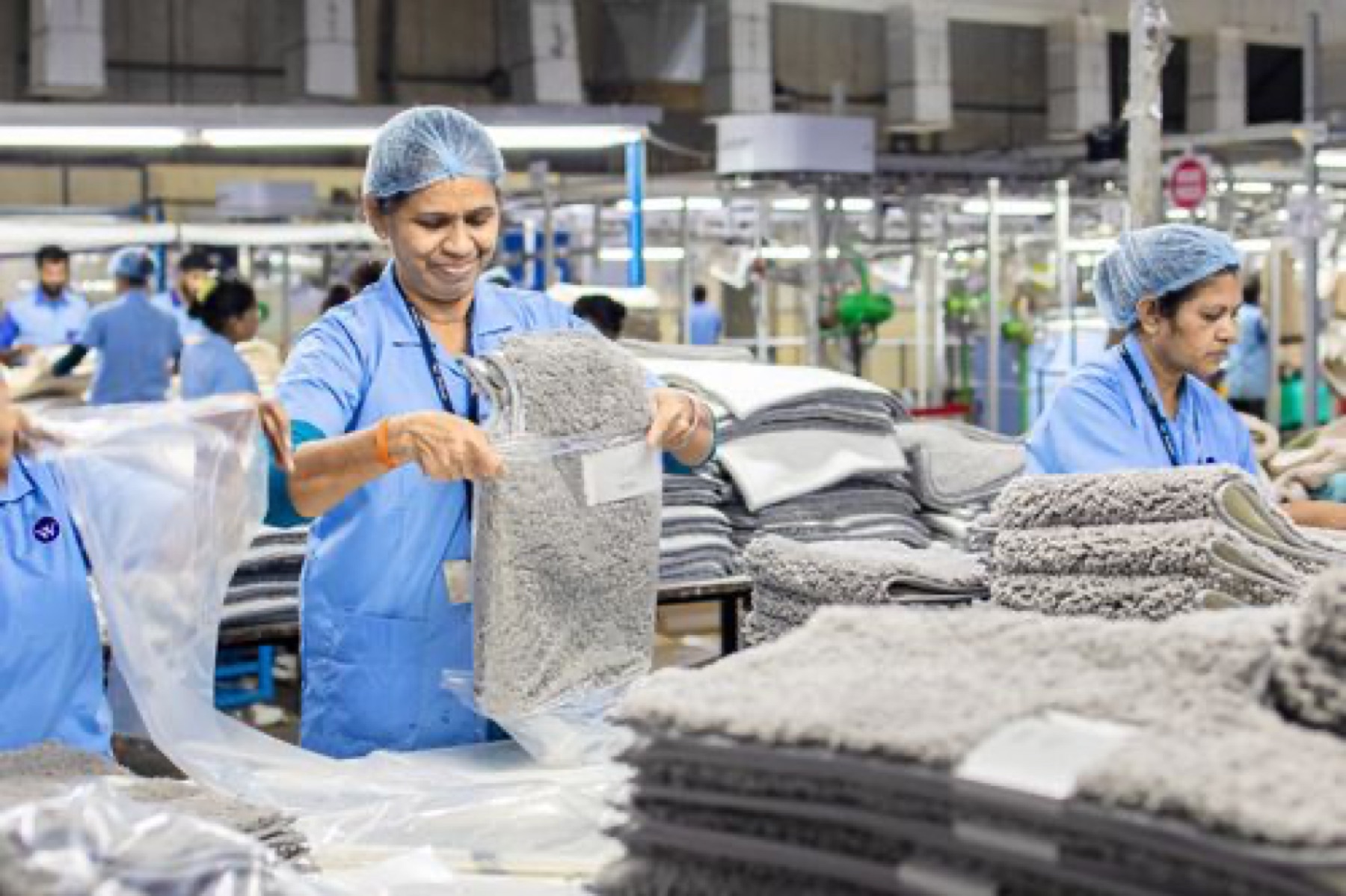 Workers in a textile factory organizing rugs, illustrating the upstream side of area rug sourcing