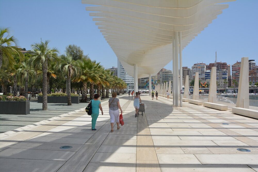 Málaga promenade with people walking along the waterfront and city buildings in the background