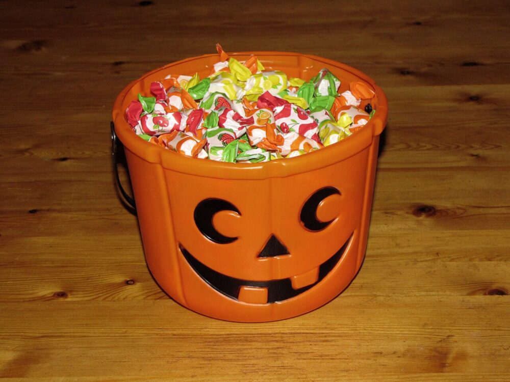 Halloween candy bucket on a wooden floor, illustrating themed trick-or-treat containers.