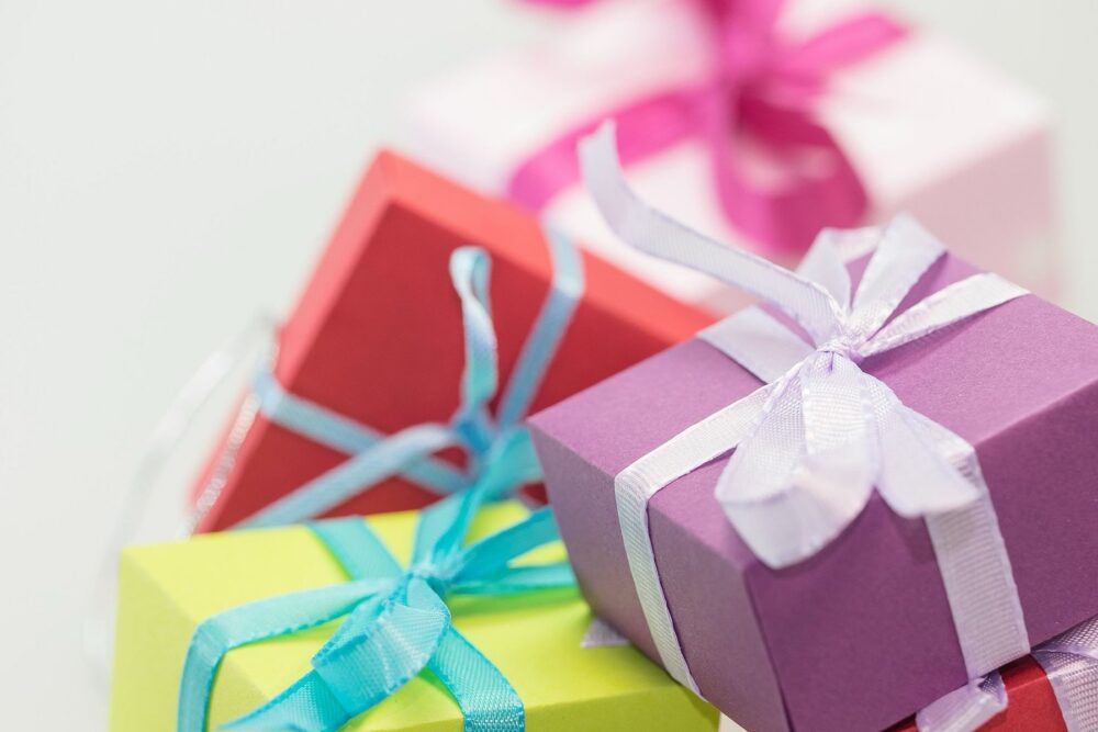 Wrapped Christmas gifts stacked near a tree, illustrating festive stocking stuffer sourcing.
