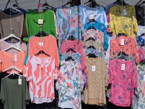 Colorful tops hanging on an outdoor clothing rack, illustrating mixed wholesale apparel stock