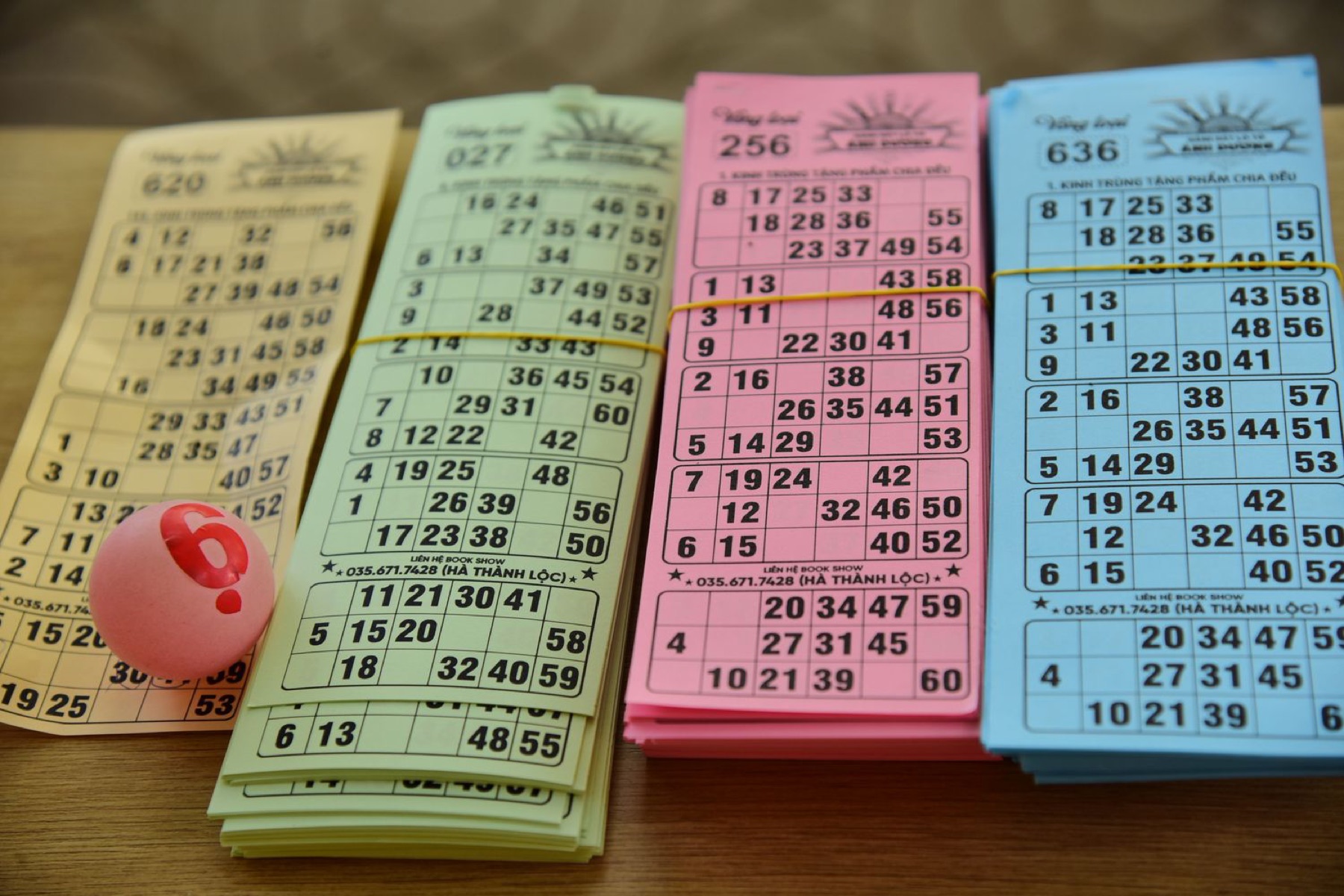Colorful bingo cards and numbered ball on a table, illustrating a typical bingo setup where dabbers are used