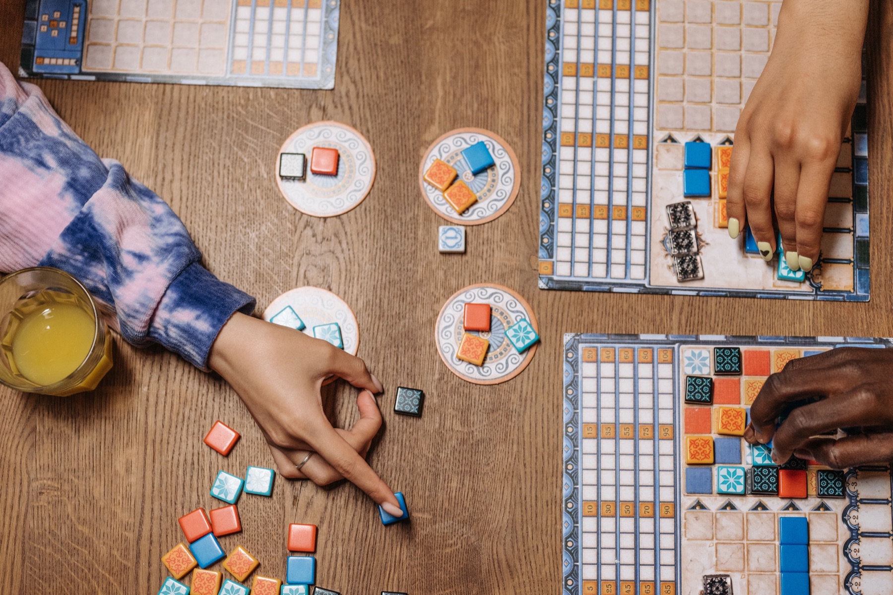 Person comparing board game prices on a laptop with a stack of tabletop games nearby