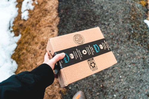 Amazon package being carried by a delivery worker, representing FBA inventory in transit