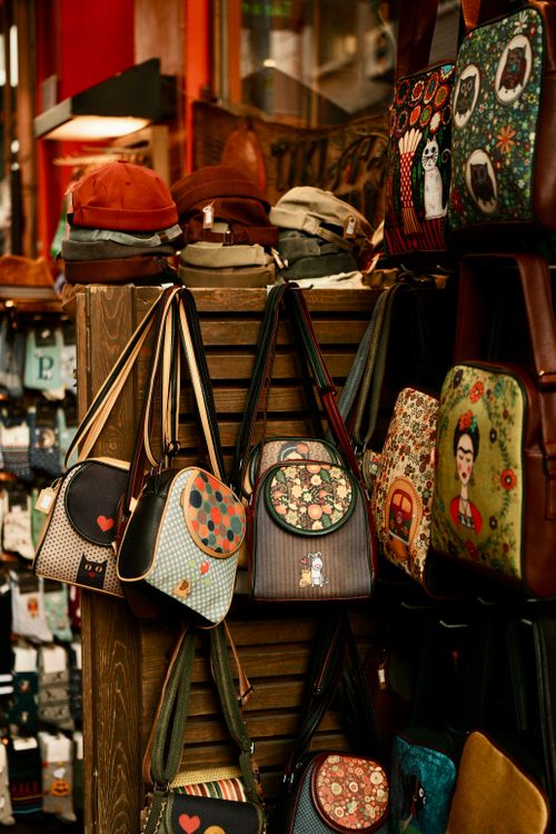 Assorted colorful bags and hats displayed on a rack, illustrating the variety of low- to mid-priced bags and accessories