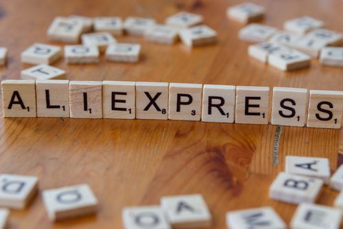 Scrabble tiles spelling “AliExpress” on a wooden table, symbolizing marketplace-based dropshipping