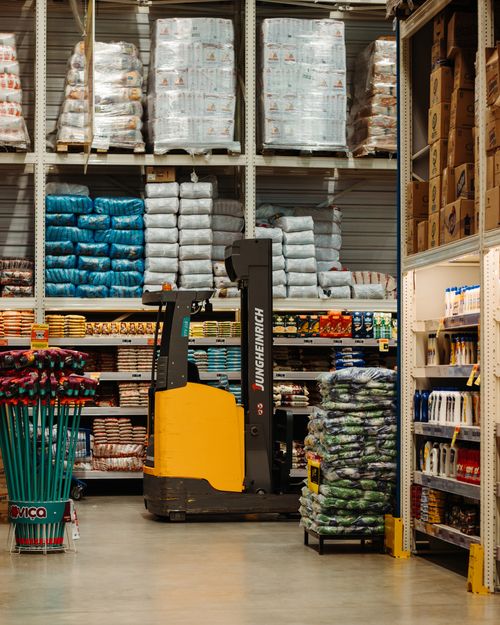 Busy wholesale market stalls with stacked products and buyers walking the aisles