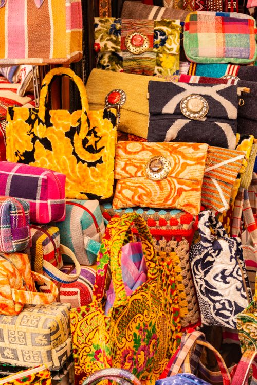 Pile of colorful bags stacked at a stall, illustrating different styles and uses of low- to mid-priced bags