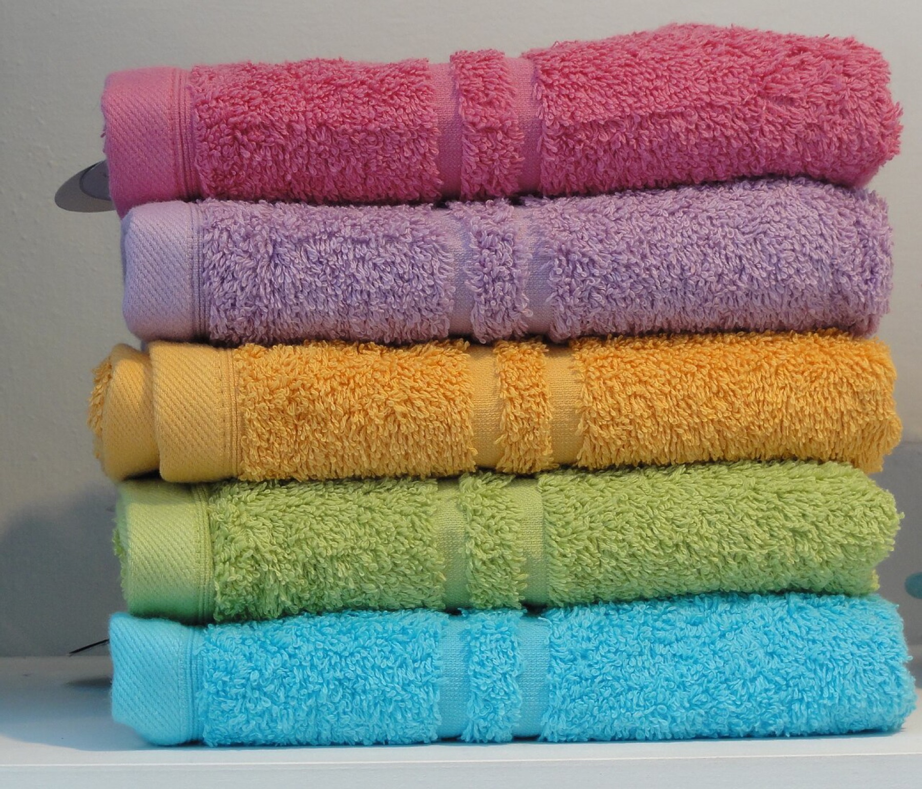 Stack of folded towels on a neutral surface, emphasizing the importance of matching rack capacity and dimensions to real towel sizes.