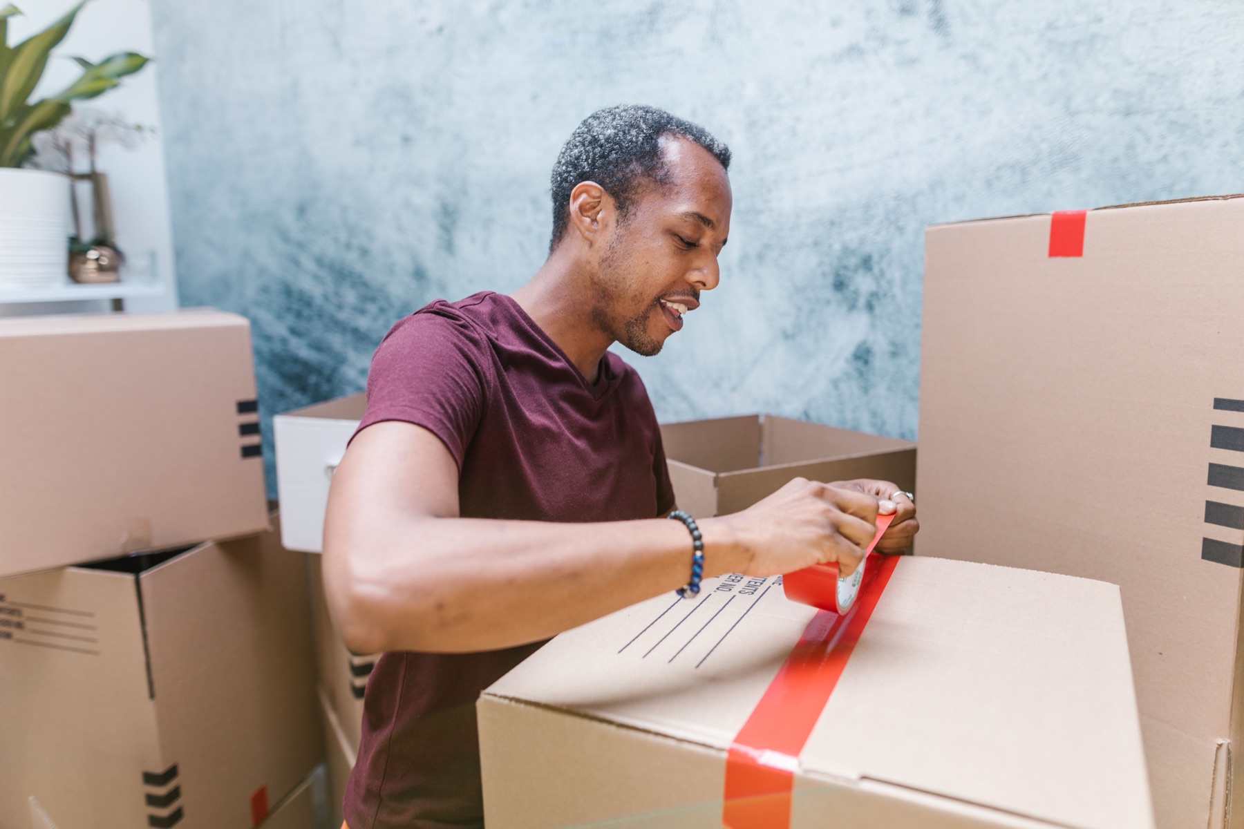 Person sealing a cardboard box with tape on a workbench