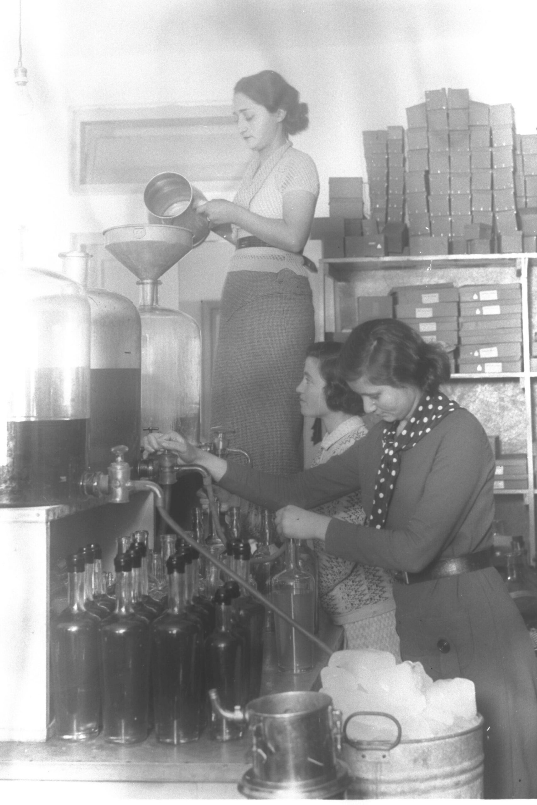 Workers filling perfume bottles on a cosmetics factory production line