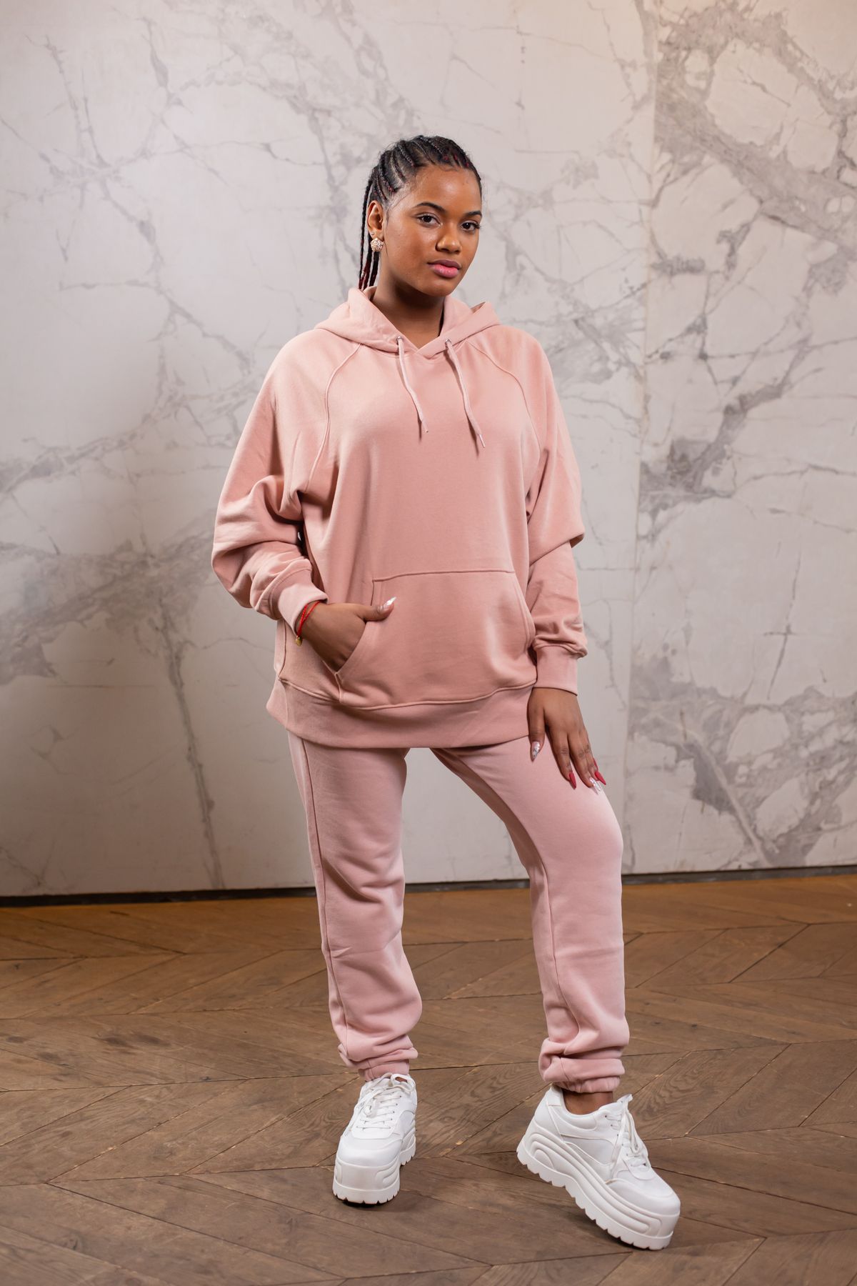 Woman wearing a pink hoodie and matching cuffed sweatpants with white sneakers
