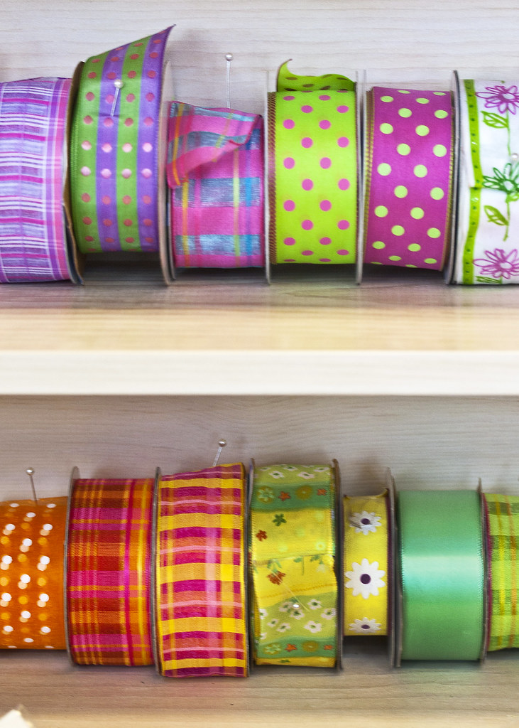 Rows of colorful patterned ribbon rolls arranged on wooden shelves