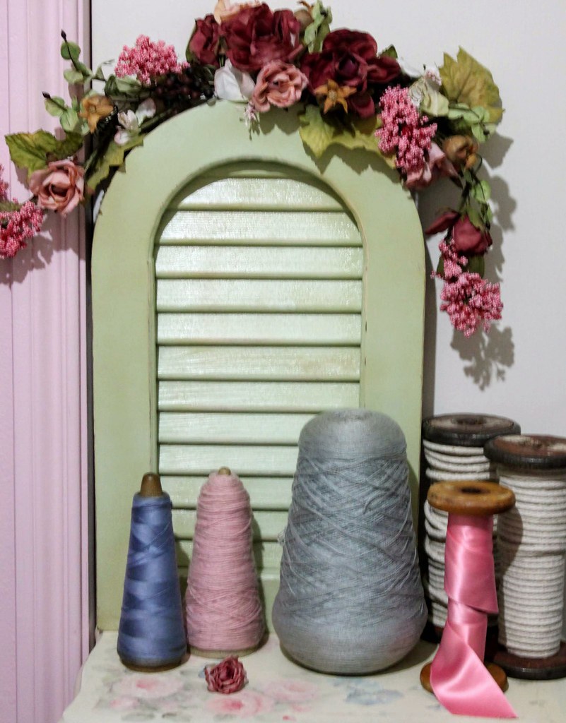 Vintage thread spools with a pink satin ribbon beside them