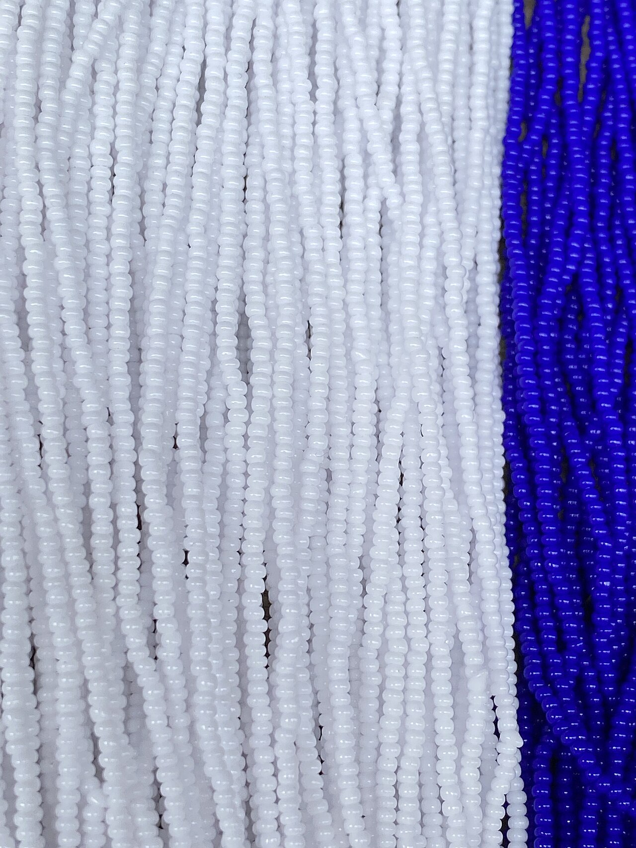 Close-up of small white and blue craft beads used as a visual reference for sorting tiny decorative components