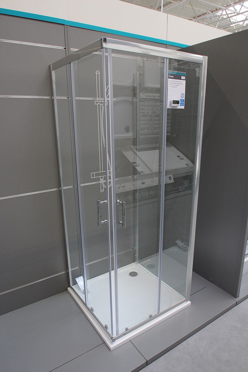 Clear-glass shower enclosure with a metal perimeter frame and paired handles in a shop display