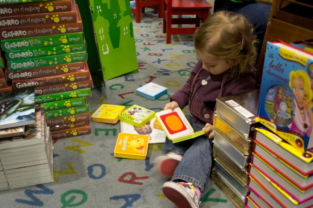 A toddler reading board books on the floor of a bookstore