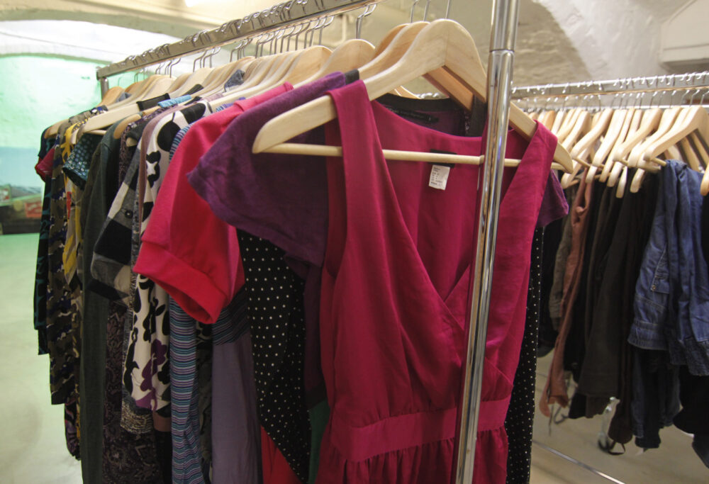 Assorted shirts and clothing displayed on wooden hangers on a rack