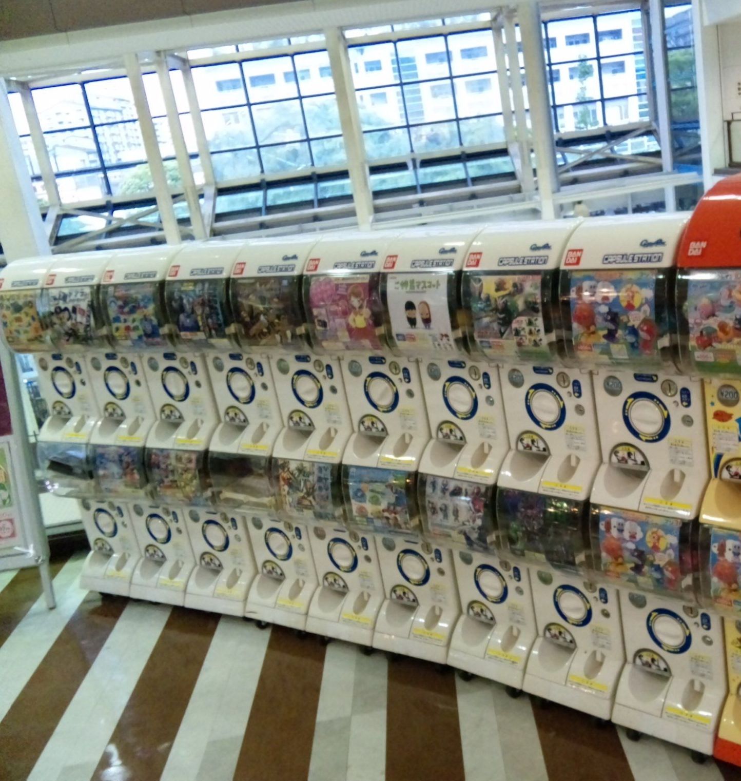 Rows of Japanese capsule toy vending machines displaying randomized collectible figures