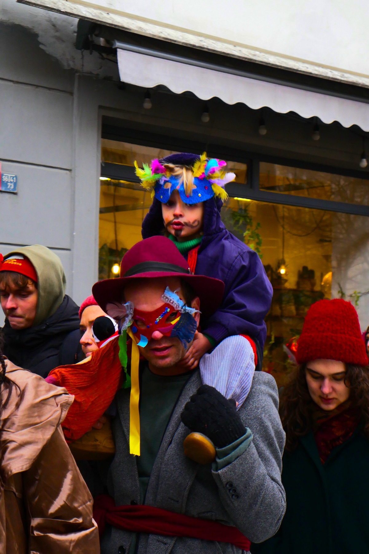 Child wearing a decorative mask during a colorful street carnival