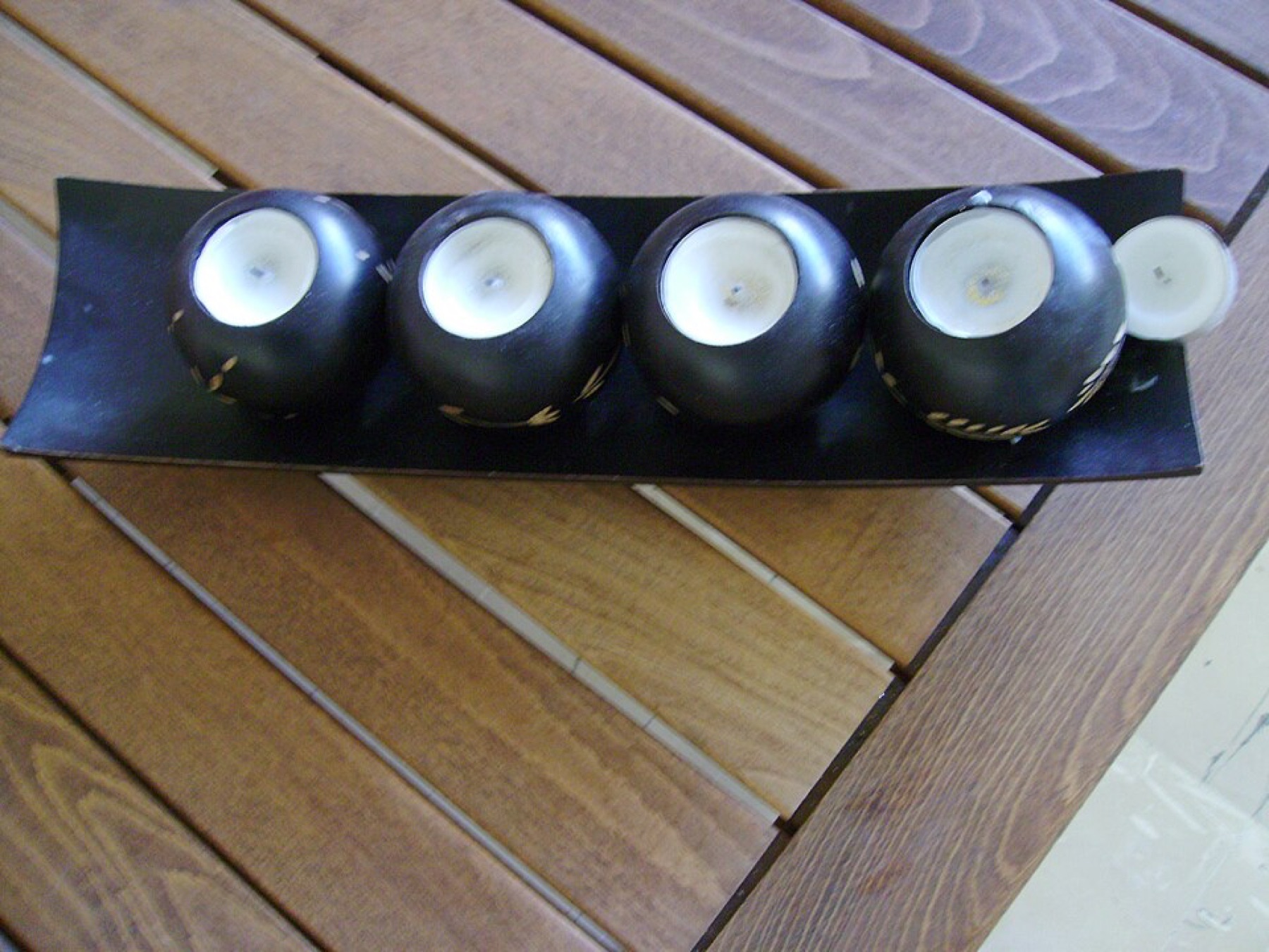 Four round tealight candle holders arranged on a wooden table