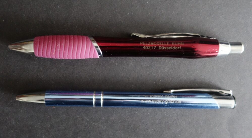 Two promotional pens with printed logos placed on a flat surface