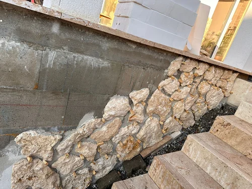 Travertine rockface veneer installed along an exterior wall