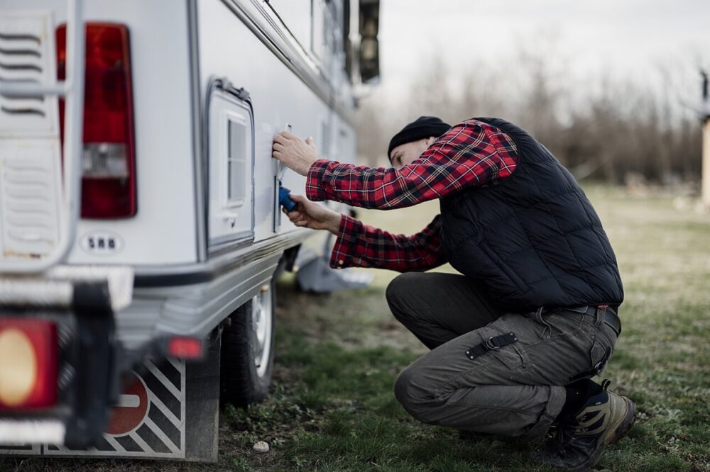 A technician repairing a camper van outdoors, illustrating the fit and maintenance context for RV replacement parts