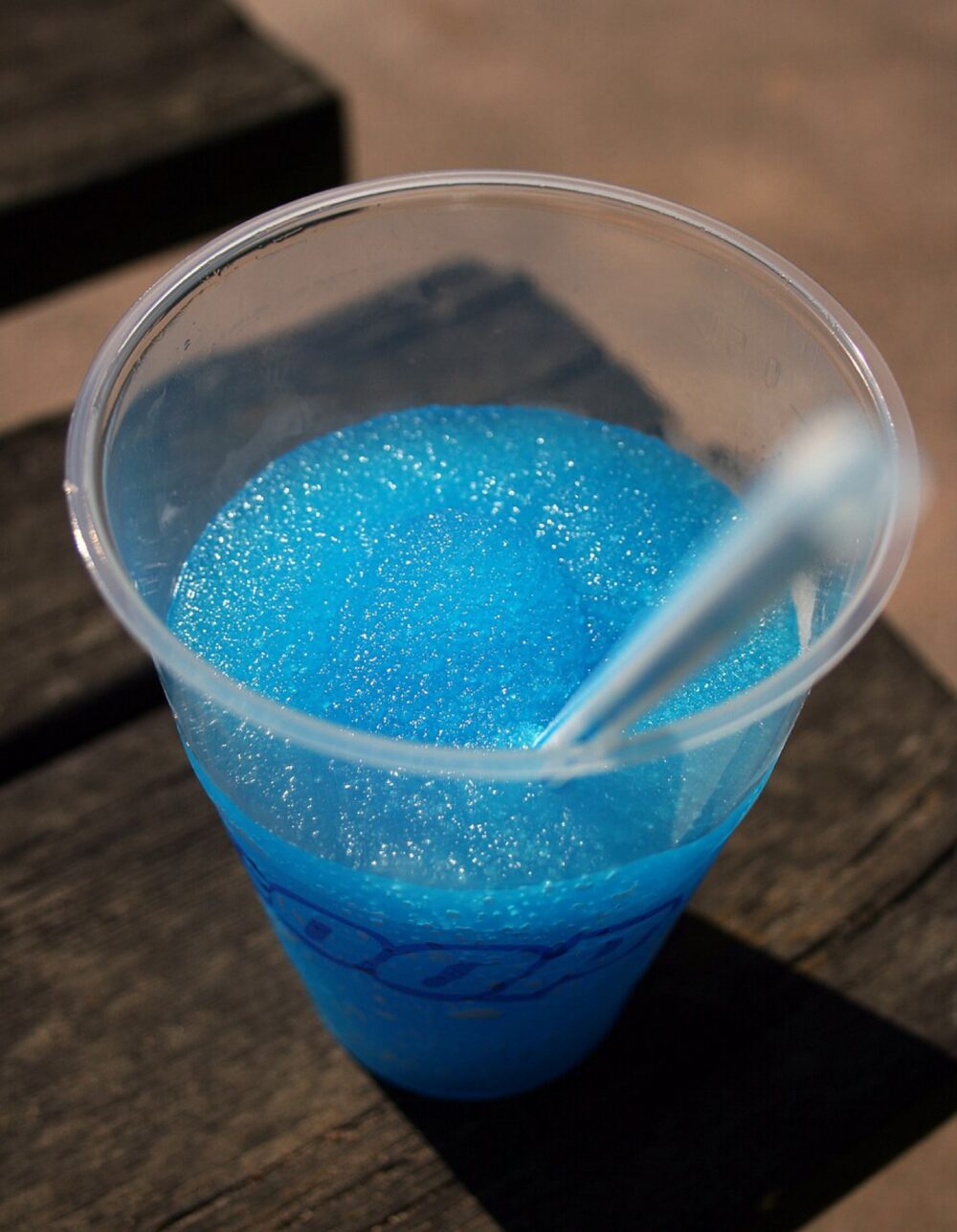 Blue slush drink in a clear plastic cup with a straw