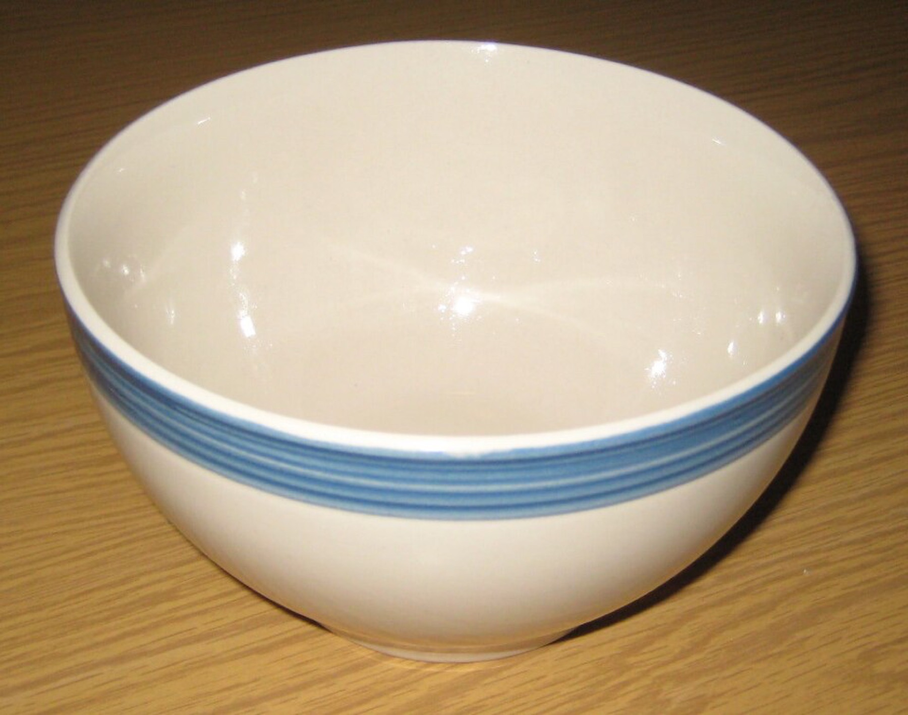 Simple ceramic bowl with a blue glazed trim illustrating the material and finish buyers should specify