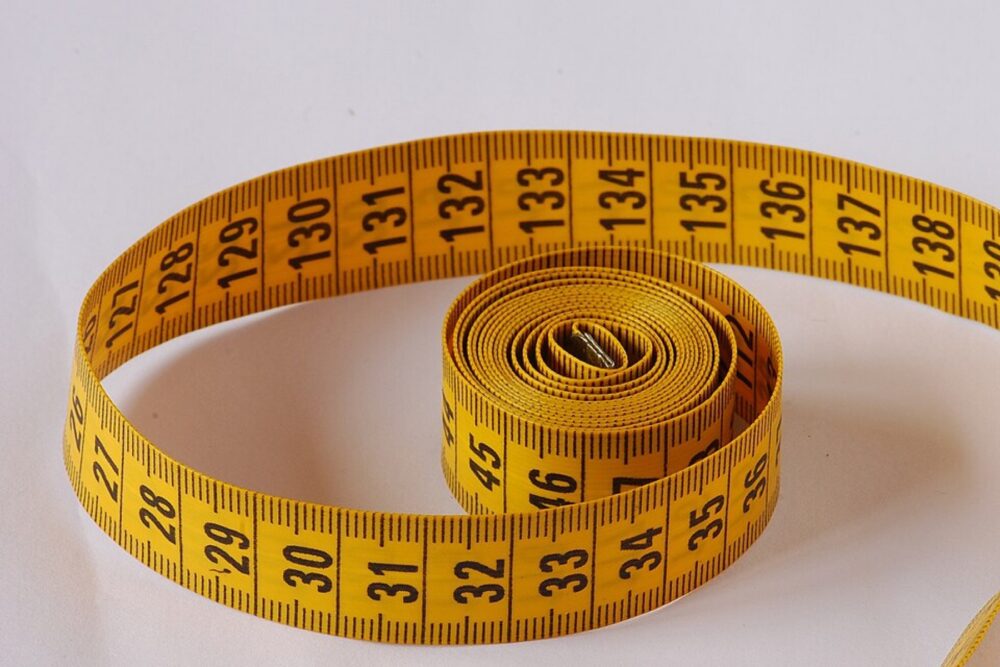 Yellow flexible tape measure coiled on a white surface