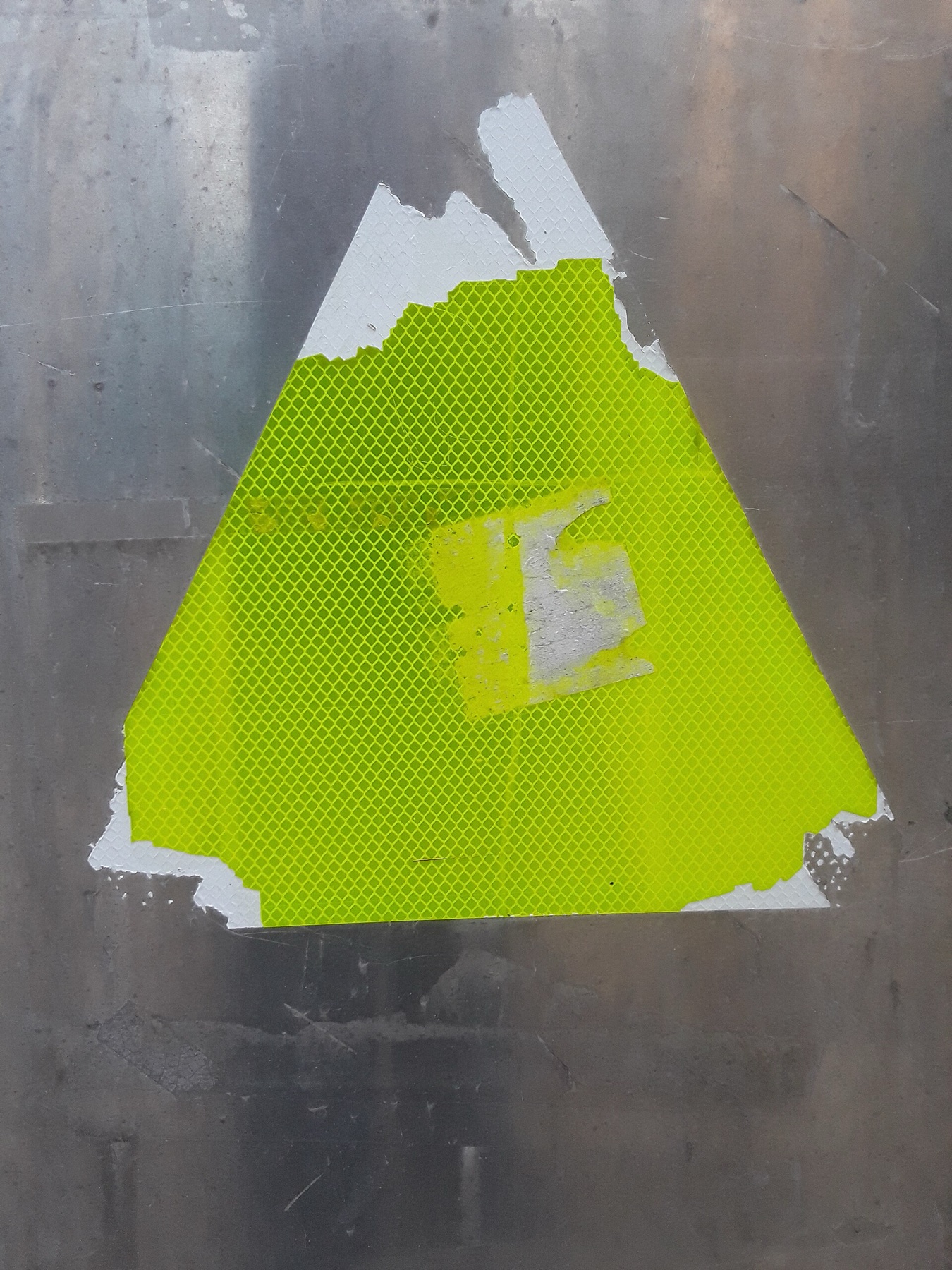 Weathered yellow sticker illustrating outdoor adhesive wear