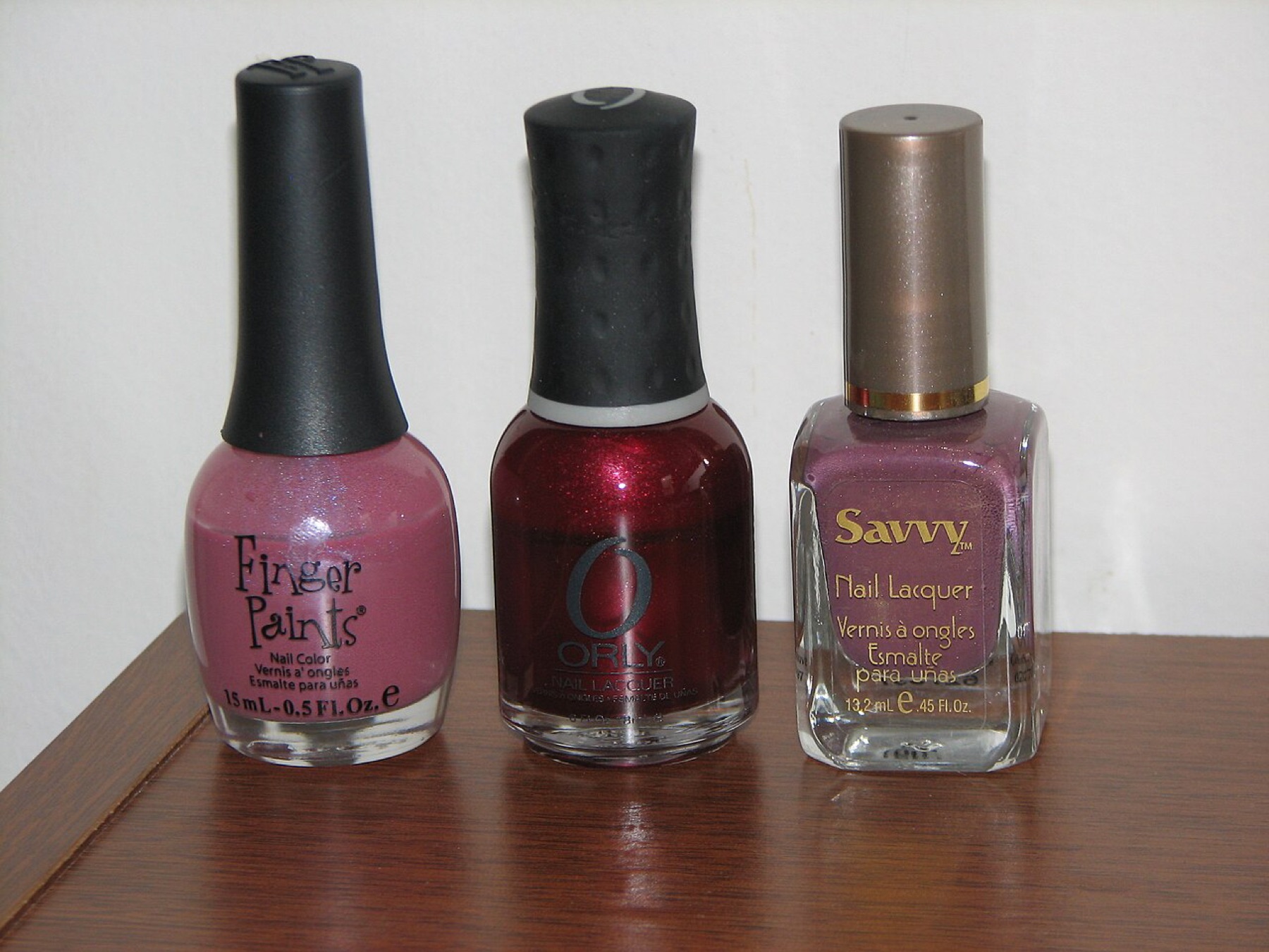 Rows of differently colored nail polish bottles on a reflective surface