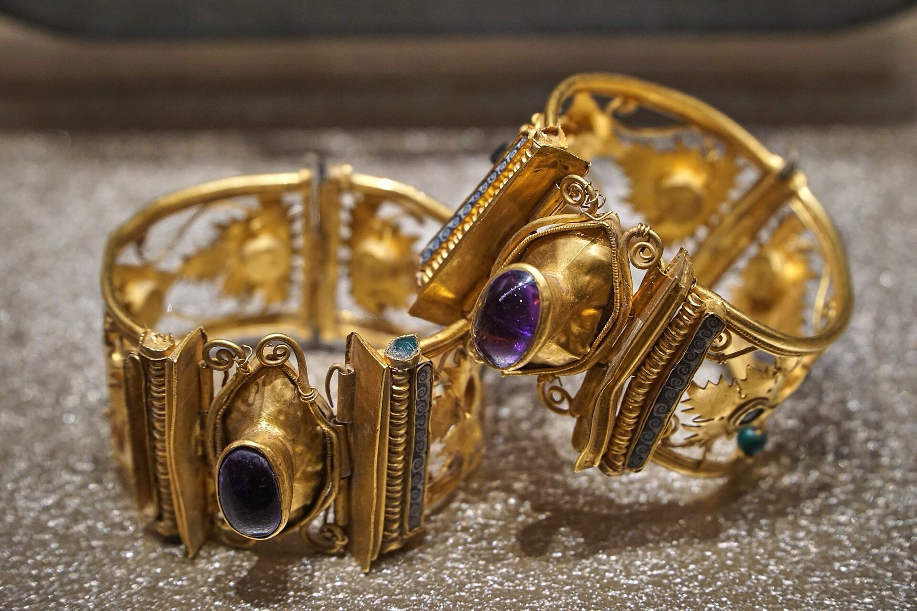 Gold bracelets displayed side by side in a museum case