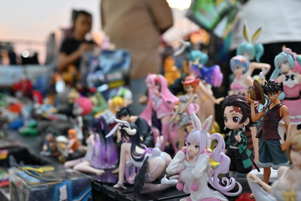 Colorful anime figurines arranged on a busy convention table, showing the variety of character merchandise wholesalers might supply