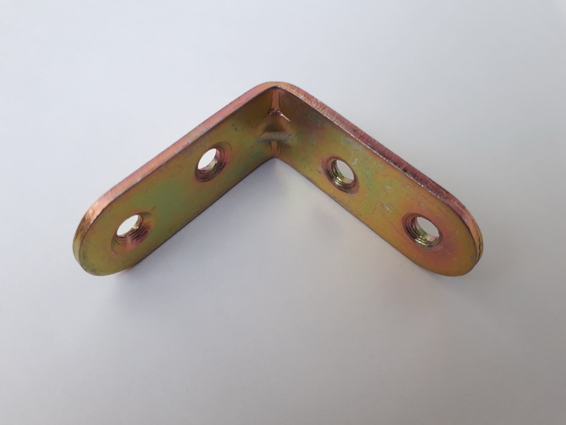 Small bronze angle bracket resting on a flat surface