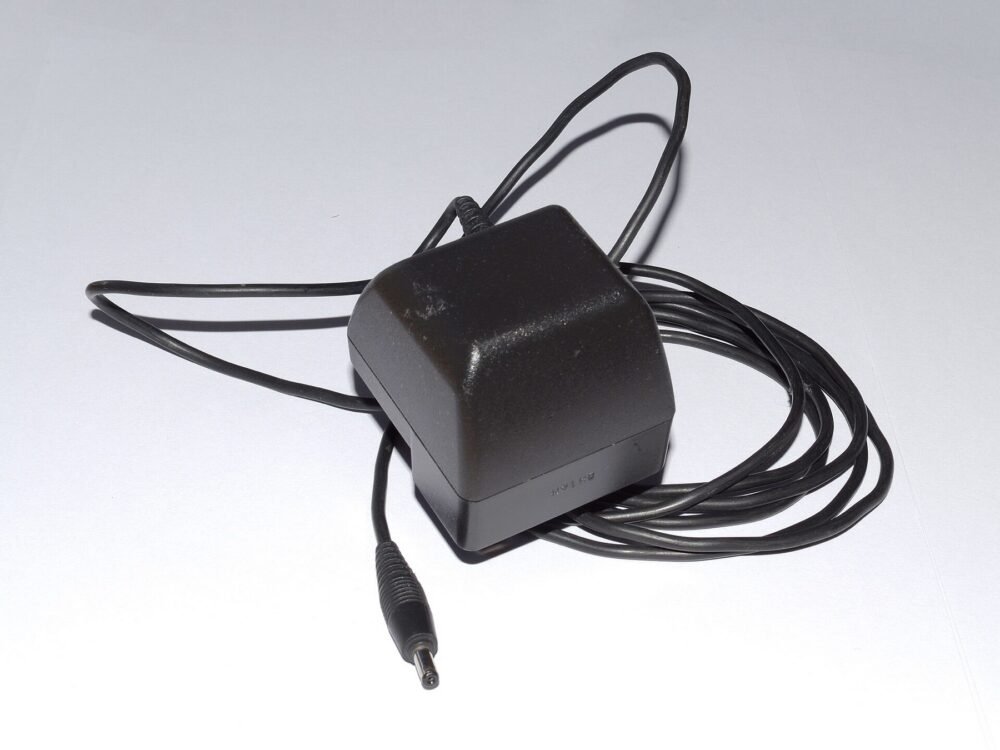 Close-up view of a classic phone charger plugged into a UK outlet