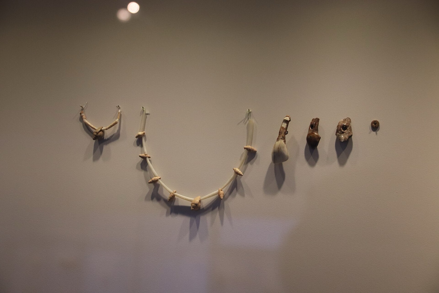 Display of ancient stone jewelry pieces in a museum case.