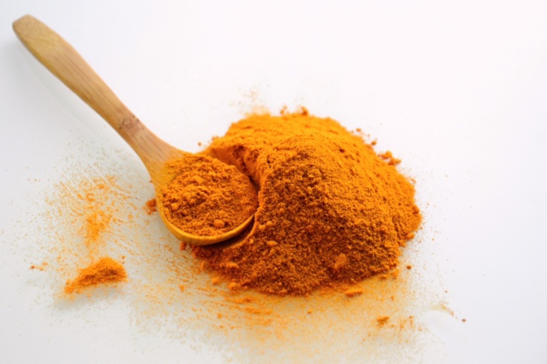 Bright orange turmeric powder in a small bowl, showing the core ingredient used in turmeric soap formulations.