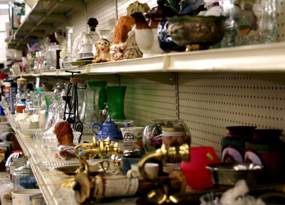 Assorted clothing and household items on thrift store shelves
